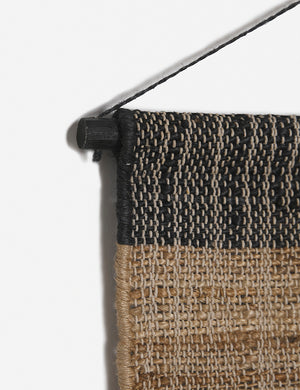 Close-up of the hanging pole on the top of the Katlee black and natural flat weave Wall Hanging
