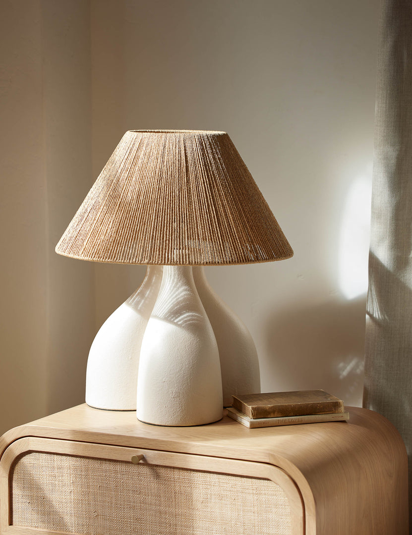 #color::gray | Gustav woven shade sculptural table lamp styled on a light wood cane front nightstand.