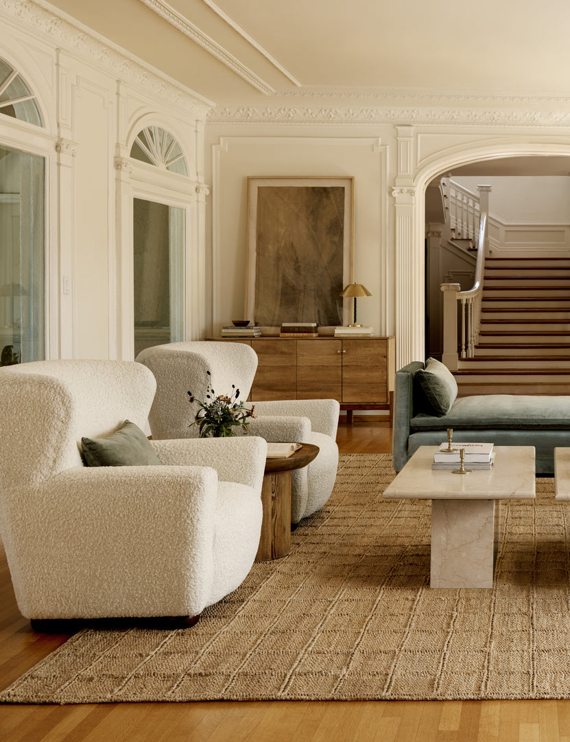 #color::boucle-cream | Two Avery Boucle Cream accent chairs sit next to each other atop a textured jute rug with two stone coffee tables atop it