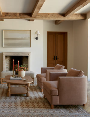 Two Belmont apricot linen accent chairs sit next to each other atop a patterned rug with a round coffee table across from them