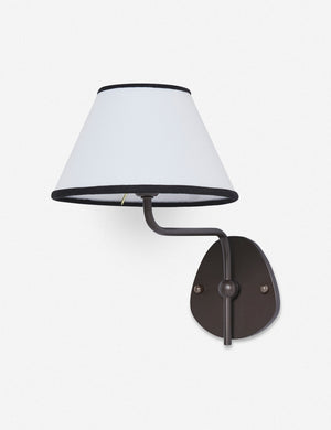 Magdalene black single sconce with a white linen shade that has a black trim, a round wall mount, and an arched arm