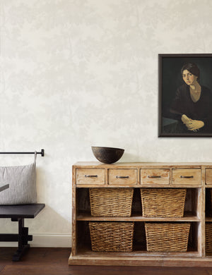 The Scalamandre botanical inspired white raphael wallpaper is in a room with a portrait artwork and a wooden sideboard