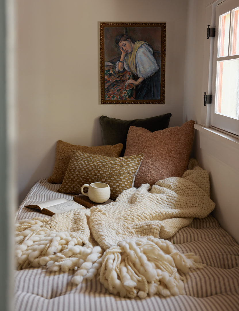 #color::terracotta #size::20--x-20- | The Manon linen terracotta orange square boucle pillow sits on a striped cushioned bench with other throw pillows in a nook