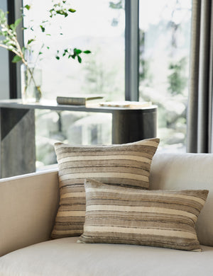 The Danique earth-toned striped silk throw pillow in its lumbar and square sizes sit on an ivory linen sofa together