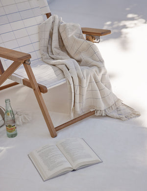 Pop check Beach Towel by Business & Pleasure Co hangs on a beach chair next to a book