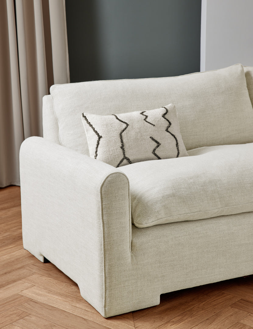 #color::natural-linen #size::103-W | The Rupert natural linen sofa sits in a studio room with an ivory flatweave pillow with black accents sitting atop it