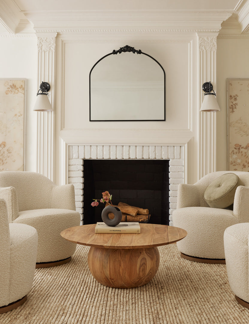 #color::natural-boucle | Four natural boucle margie swivel chairs sit around a wooden circular coffee table atop a sand Kenzi rug.