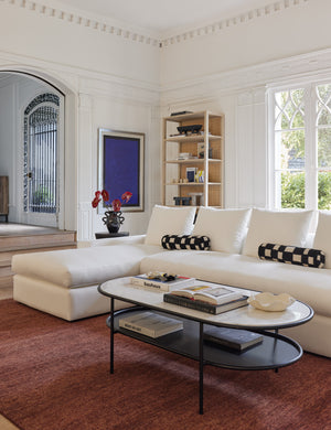 Two of the Irregular black and white Checkerboard Bolster Pillows by Sarah Sherman Samuel sit on a white sectional in a living room with pops of color