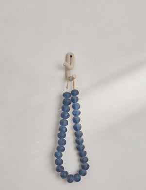 Cream speckled Leggy Crossed Wall Hook by SIN Ceramics with a blue beaded necklace hanging from it