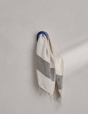 The olo cobalt blue wall hook hangs on a wall with a towel