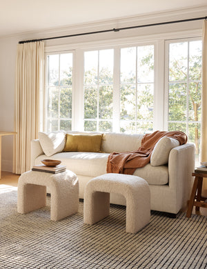 The Uma black and natural checkered grid pattern rug lays under a natural linen sofa and two cream boucle benches in a living room