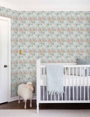 Dark-toned Floral Field Wallpaper by Rylee + Cru is in a nursery with a toy lamb and a white wooden crib