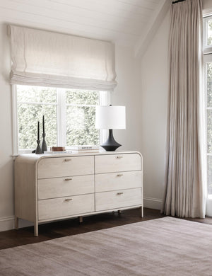 The dusk dylan rug lays in a bedroom with a white sloped ceiling next to a six-drawer white washed dresser under a window