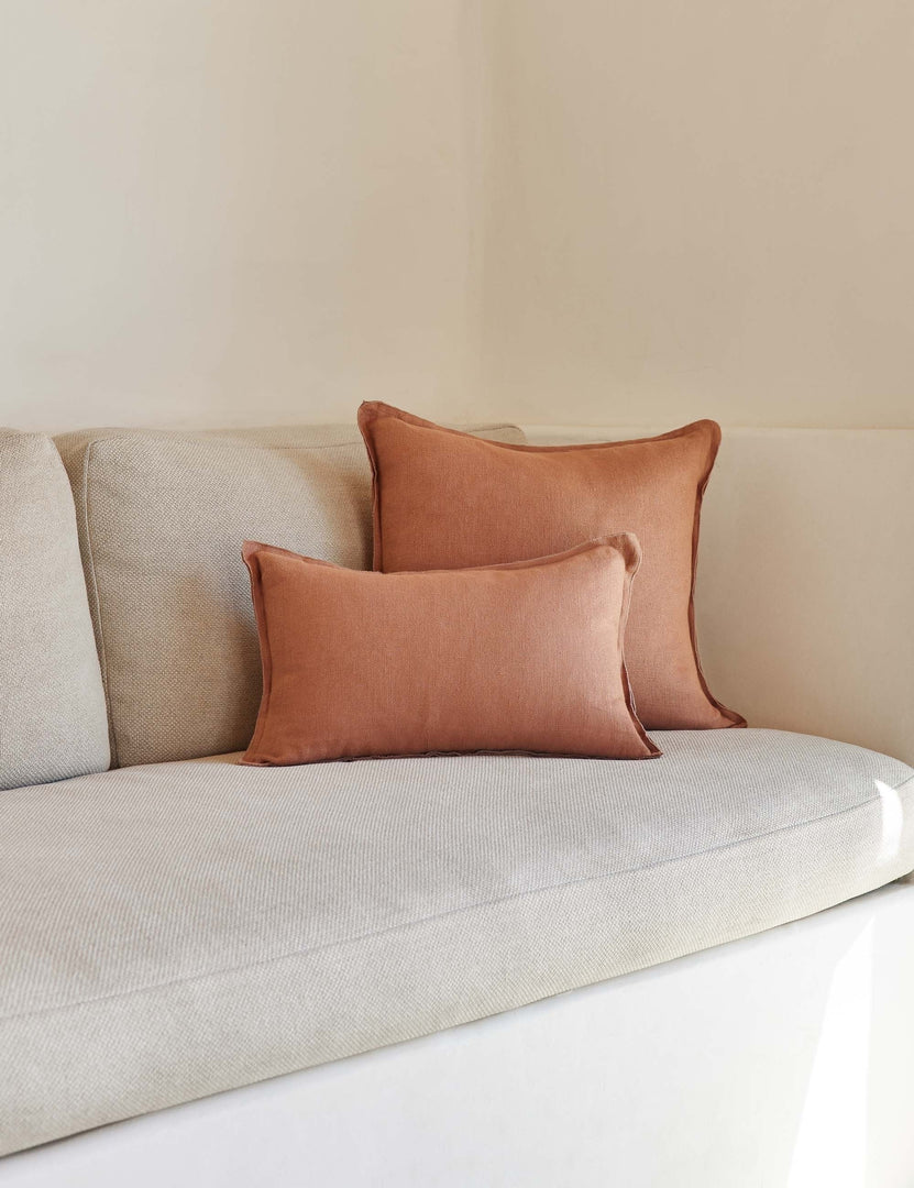 #color::rust #style::lumbar #fill type::with-feather-down-insert #fill type::pillow-cover-only | The arlo rust orange flax linen pillow in its lumber and square sizes sit together on a natural linen sofa