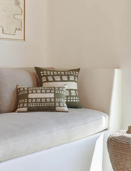 #size::12--x-20- | The Stonewalk green geometric throw pillow by Élan Byrd sits on a natural linen cushioned bench next to a jute basket