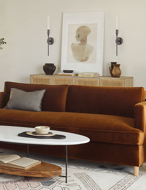 The Sara singh back drop portrait neutral toned wall art by Stampa sits in a living room atop a woven sideboard with a cognac velvet sofa and a geometric rug
