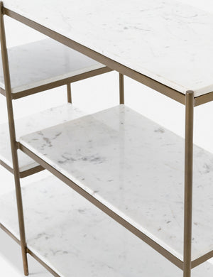Angled close-up of the shelving on the right side of the Kathleen console table with marble shelves and gold finish