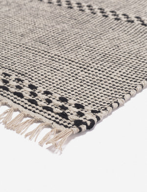 Corner shot of the Masha gray and black geometric machine washable mat with tasseled ends