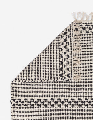 Corner shot of the Masha gray and black geometric machine washable mat with tasseled ends