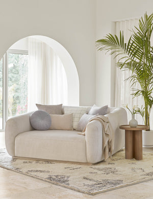 The claudette blue square pillow sits atop an ivory linen media lounger in a room with high white