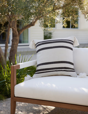The Fez black and white indoor and outdoor throw pillow sits on a white sofa in an outdoor space