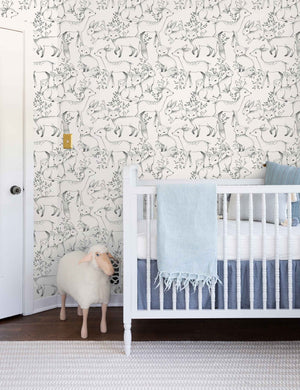 The Woodland Wallpaper by Rylee + Cru is in a children's room with a sheep toy and a white crib with ivory and blue linens