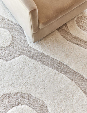 Close-up of the Oasis plush geometric neutral-toned rug by Élan Byrd underneath a light brown velvet sofa