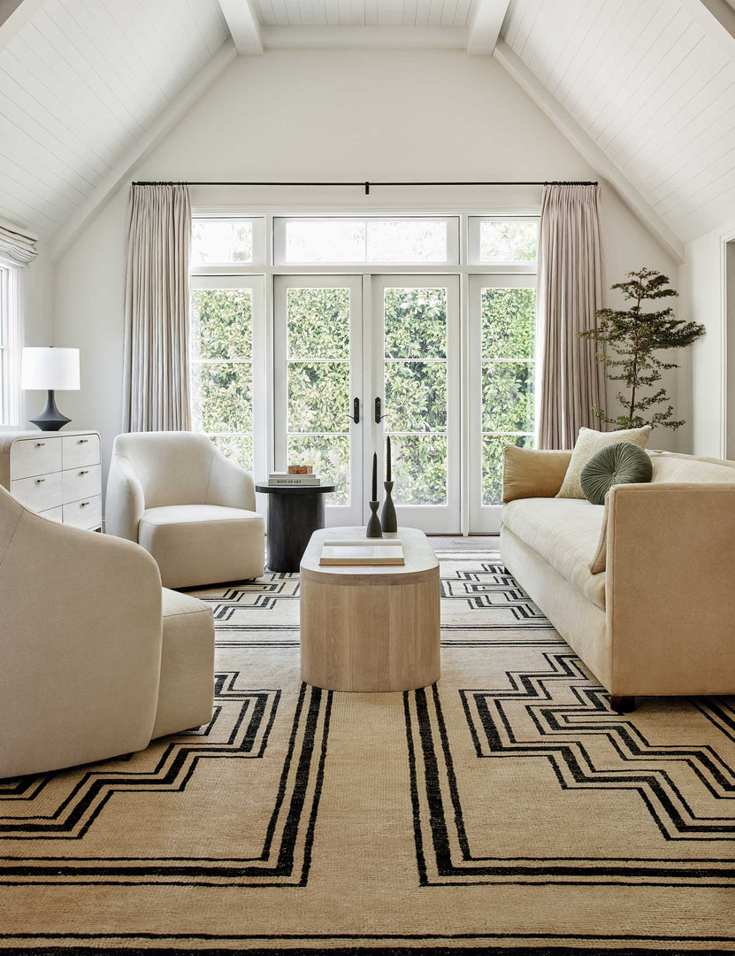 #color::natural | Two Tobi natural linen swivel chairs sit next to each other atop a black and natural geometric rug across from a linen sofa