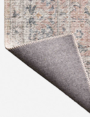 Close-up of the corner of the Roze blush and grey power-loomed rug with medallion patterns with the bottom folded over