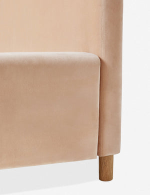 Close-up of where the headboard, oak leg, and base of the Solene buff pink velvet platform bed meet