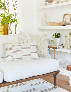 Stripe break natural and cream lumbar pillow by Sarah Sherman Samuel sits on a white sofa with a plush white pillow behind it