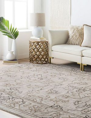 The Vivienne white ceramic table lamp with spherical base sits in a living room atop a metal patterned side table, a plush patterned rug, and a white sofa